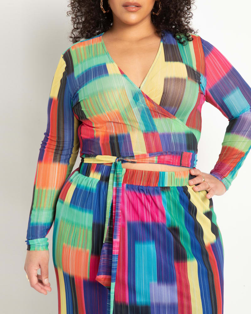 Side of a model wearing a size 18|20 Mesh Long Sleeve Wrap Top in Psychedelic Blocks by ELOQUII. | dia_product_style_image_id:290212